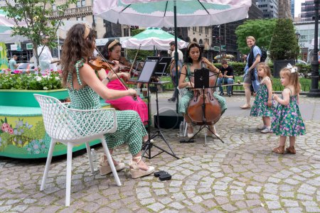 Photo for Fifth Avenue Blooms. May 13, 2023, New York, New York, USA: Young girls watch musicians play during the Fifth Avenue Blooms imagined by Van Cleef event at Pulitzer Fountain on May 13, 2021 in New York City. - Royalty Free Image