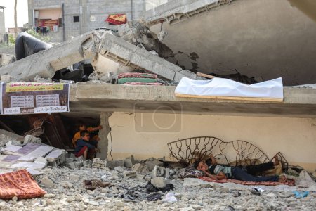 Foto de Los palestinos se sientan en su casa, que fue destruida por los aviones de ocupación israelíes. 22 de mayo de 2023, Gaza, Palestina: Palestinos de la familia Nabhan se sientan en los escombros de su casa, que fue destruida por los aviones de ocupación israelíes - Imagen libre de derechos