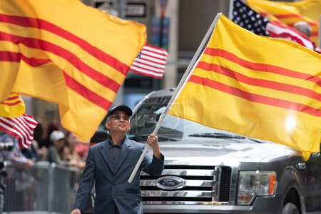 Téléchargez les photos : Homme vietnamien avec des drapeaux vietnamiens à la deuxième parade annuelle de l'AAPI sur la Sixième Avenue (Avenue des Amériques). Le 21 mai 2023. New York, États-Unis Le défilé culturel et patrimonial de l'Asian American and Pacific Islander (AAPI) a lieu à New York. - en image libre de droit