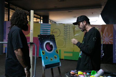 Photo for NFT Brazil -Graffiti Auction. June 04, 2023, Sao Paulo, Brazil: Skateboarder and founder of the Skate Cuida institute, Bob Burniquist creates graffiti art and auctions it off during the NFT Brasil held at Ibirapuera Park Biennial, in Sao Paulo. - Royalty Free Image