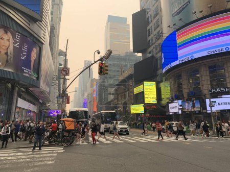 Foto de Time Square-NYC Under Smoke from Canada 's Fires (en inglés). 7 de junio de 2023, Nueva York, Estados Unidos: Todo el aire de la ciudad de Nueva York ha sido contaminado con humo proveniente de Canadá, causando que los neoyorquinos y turistas en Times Square se oculten para evitar ser contaminados - Imagen libre de derechos