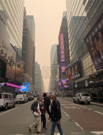 Foto de Time Square-NYC Under Smoke from Canada 's Fires (en inglés). 7 de junio de 2023, Nueva York, Estados Unidos: Todo el aire de la ciudad de Nueva York ha sido contaminado con humo proveniente de Canadá, causando que los neoyorquinos y turistas en Times Square se oculten para evitar ser contaminados - Imagen libre de derechos