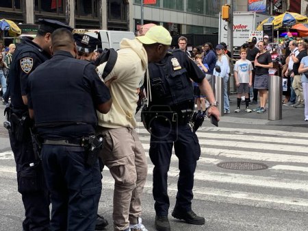 Téléchargez les photos : La police arrête des trafiquants illégaux à Time Square. 15 juin 2023, New York, États-Unis : La police de New York est en pleine force pour nettoyer tout trafic illégal en cours à Times Square alors qu'ils arrêtent deux suspects et les emmènent au poste de police voisin - en image libre de droit