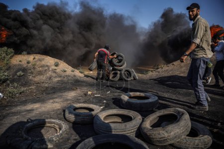 Téléchargez les photos : Des jeunes Palestiniens ont mis le feu à des pneus en caoutchouc aux frontières orientales de la bande de Gaza. 19 juin 2023, Gaza, Palestine : Des jeunes Palestiniens incendient des pneus en caoutchouc aux frontières de la bande de Gaza - en image libre de droit