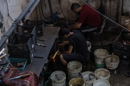 Téléchargez les photos : Préparation de l'Aïd al-Adha. 25 juin 2023 Gaza, Palestine : Des travailleurs palestiniens travaillent à l'intérieur de la boutique Al-Fari au centre de la bande de Gaza, spécialisée dans l'affûtage et la préparation de couteaux et d'outils tranchants pour les bouchers palestiniens - en image libre de droit