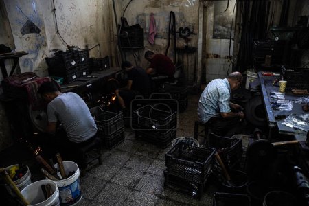Téléchargez les photos : Préparation de l'Aïd al-Adha. 25 juin 2023 Gaza, Palestine : Des travailleurs palestiniens travaillent à l'intérieur de la boutique Al-Fari au centre de la bande de Gaza, spécialisée dans l'affûtage et la préparation de couteaux et d'outils tranchants pour les bouchers palestiniens - en image libre de droit