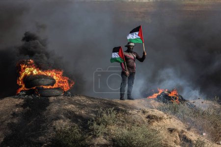 Téléchargez les photos : (INT) Des jeunes Palestiniens ont mis le feu à des pneus en caoutchouc le long de la frontière orientale de la bande de Gaza. 3 juillet 2023, Gaza, Palestine : Des jeunes Palestiniens brûlent des pneus en caoutchouc à la frontière Est de Gaza pour exprimer leur colère - en image libre de droit