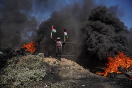 Photo for (INT) Palestinian youths set fire to rubber tires along the eastern border of the Gaza Strip. July 3, 2023, Gaza, Palestine: Palestinian youths are burning rubber tires on the eastern Gaza border to express their anger - Royalty Free Image