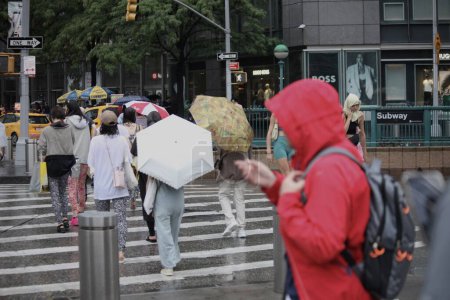 Foto de Los neoyorquinos celebran la independencia del 4 de julio bajo las lluvias. 4 de julio de 2023, Nueva York, Estados Unidos: Muchos neoyorquinos y turistas que tuvieron que improvisar diferentes formas de protección contra la lluvia, fueron sorprendidos con la guardia baja cuando se quedaron varados en la estación de metro - Imagen libre de derechos