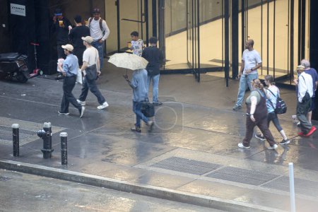 Téléchargez les photos : New York, États-Unis - 24 août 2023 : Pluie à New York. Le changement soudain de temps apportant des averses de pluie forçant les New-Yorkais et les touristes à se protéger avec des parapluies, des ponchos dans leurs activités quotidiennes. - en image libre de droit