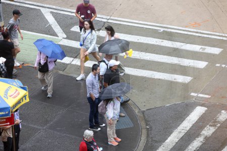 Foto de Nueva York, EE.UU. - 24 de agosto de 2023: Lluvias en la ciudad de Nueva York. El repentino cambio de clima que trae consigo lluvias que obligan a neoyorquinos y turistas a protegerse con sombrillas, ponchos mientras realizan sus negocios diarios. - Imagen libre de derechos