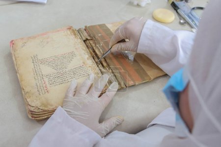 Photo for September 06, 2023 - Gaza, Palestine: Palestinian researcher repairing and archiving ancient books and manuscripts in Gaza City. A team of Palestinian researchers from the Eyes on Heritage Foundation at work - Royalty Free Image