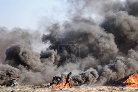 Foto de Manifestantes palestinos queman neumáticos durante una protesta contra los repetidos ataques a los patios de la mezquita Al-Aqsa. 22 de septiembre de 2023. Gaza, Palestina: - Imagen libre de derechos