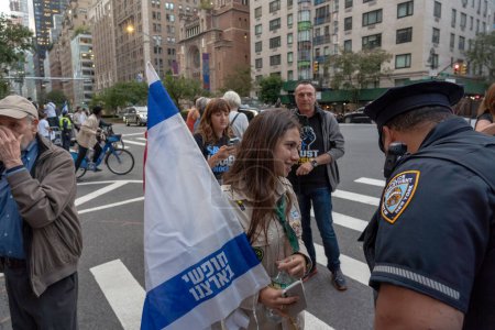 Foto de Expatriados israelíes y judíos estadounidenses protestan durante la visita del Primer Ministro Netanyahu a la ONU. 21 de septiembre de 2023, Nueva York, Nueva York, Estados Unidos: Un miembro de los exploradores israelíes con una bandera israelí habla con un oficial de policía de Nueva York - Imagen libre de derechos