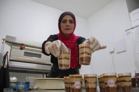 Téléchargez les photos : La Palestinienne Ayat Mutair, 40 ans, qui souffre d'une déficience auditive, fabrique des bonbons dans son magasin. 28 septembre 2023. Gaza, Palestine - en image libre de droit