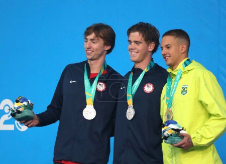 Photo for SANTIAGO, CHILE - 10/23/2023: Medal ceremony in the men's 100M Freestyle won by the Brazilian GUILHERME SANTOS (Gold) and the Americans BROOKS CURRY and JONATHAN KULOW (Silver) at the Aquatic Center of the National Stadium, Santiago, Chile - Royalty Free Image