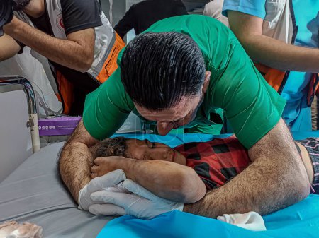 Téléchargez les photos : GAZA (PALESTINE), 30 / 10 / 2023 - Des équipes médicales du Croissant-Rouge palestinien secourent des enfants des décombres alors qu'ils attaquent un bâtiment au sud de la ville de Gaza, dans la province de Khan Yunis - en image libre de droit
