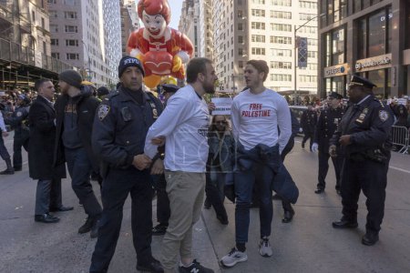 Téléchargez les photos : Les manifestants pro-palestiniens forcent Macy's Thanksgiving Day Parade à s'arrêter. 23 novembre 2023, New York, New York, USA : Un manifestant est arrêté alors que le défilé de l'Action de grâces de Macy's a été temporairement interrompu après une poignée de manifestants pro-palestiniens - en image libre de droit
