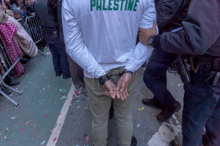 Téléchargez les photos : Les manifestants pro-palestiniens forcent Macy's Thanksgiving Day Parade à s'arrêter. 23 novembre 2023, New York, New York, USA : Les manifestants en état d'arrestation sont emmenés par les policiers de la police de New York et le défilé de l'Action de grâces de Macy's - en image libre de droit