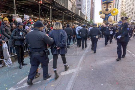 Téléchargez les photos : Les manifestants pro-palestiniens forcent Macy's Thanksgiving Day Parade à s'arrêter. 23 novembre 2023, New York, New York, USA : Les manifestants en état d'arrestation sont emmenés par les policiers de la police de New York et le défilé de l'Action de grâces de Macy's - en image libre de droit