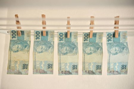Foto de Imagen ilustrativa de lavado de dinero con billetes reales colgando a secar en el tendedero. Billetes reales de R $100. - Imagen libre de derechos