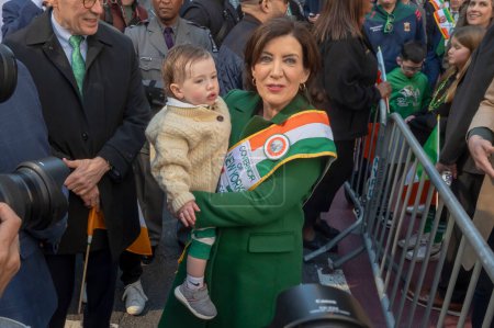 Photo for St. Patrick's Day Parade in New York City.  March 16, 2024, New York, New York, USA: New York State Governor Kathy Hochul (R) holding Seamus Carroll (16 Months old) participates in the St. Patrick's Day Parade - Royalty Free Image