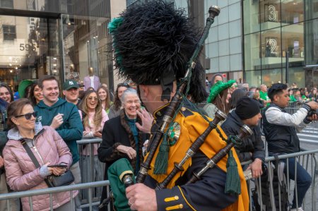 Téléchargez les photos : Parade de la Saint-Patrick à New York. 16 mars 2024, New York, New York, États-Unis : Un membre de la NYPD Emerald Society Pipes Drums salue les spectateurs lors du défilé de la Saint-Patrick le long de la 5e Avenue - en image libre de droit