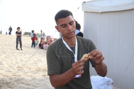 Téléchargez les photos : L'équipe de bénévoles de Gaza divertit les enfants avec Qatayef. 28 mars 2024, Khan Yunis, Gaza, Palestine : Un événement organisé par l'équipe de volontaires de Gaza sur la mer de Mawasi à Khan Yunis pour faire du Qatayef et divertir les enfants - en image libre de droit