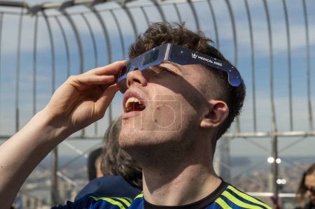 Photo for Solar Eclipse 2024 in New York City. April 08, 2024, New York, New York, USA: A boy wearing protective glasses views the partial solar eclipse from the 86th floor Observation deck of the Empire State Building on April 8, 2024 in New York City. - Royalty Free Image