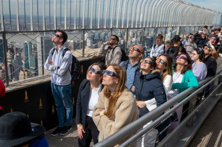 Téléchargez les photos : Solar Eclipse 2024 à New York. 08 avril 2024, New York, New York, USA : Les gens regardent une éclipse solaire partielle depuis le pont d'observation du 86ème étage de l'Empire State Building le 8 avril 2024 à New York. Avec la première éclipse solaire - en image libre de droit