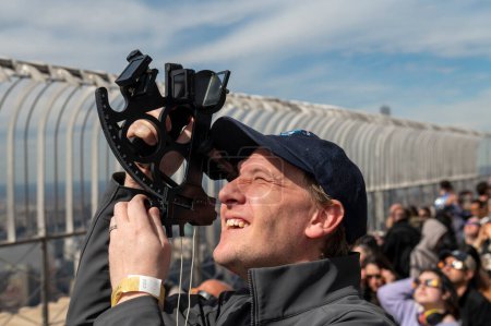 Téléchargez les photos : Solar Eclipse 2024 à New York. 08 avril 2024, New York, New York, USA : David Souther utilise un sextant pour voir l'éclipse solaire partielle depuis le pont d'observation du 86ème étage de l'Empire State Building le 8 avril 2024 à New York. - en image libre de droit