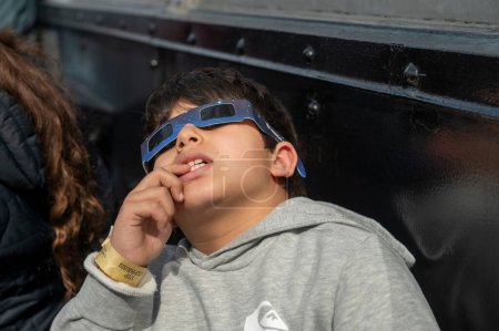 Foto de Solar Eclipse 2024 en la ciudad de Nueva York. 08 de abril de 2024, Nueva York, Nueva York, Estados Unidos: Un niño con gafas protectoras ve el eclipse solar parcial desde la cubierta de observación del piso 86 del Empire State Building el 8 de abril de 2024 en la ciudad de Nueva York. - Imagen libre de derechos