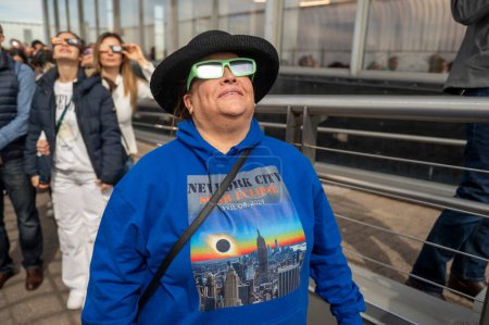 Téléchargez les photos : Solar Eclipse 2024 à New York. 08 avril 2024, New York, New York, USA : Une femme portant des lunettes de protection voit l'éclipse solaire partielle depuis le pont d'observation du 86ème étage de l'Empire State Building le 8 avril 2024 à New York - en image libre de droit
