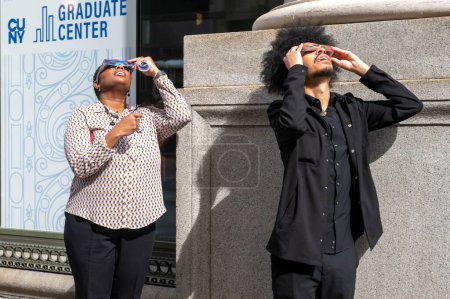 Téléchargez les photos : Solar Eclipse 2024 à New York. 08 avril 2024, New York, New York, USA : Les gens regardent une éclipse solaire partielle sur la 5e Avenue le 8 avril 2024 à New York. Avec la première éclipse solaire à traverser l'Amérique du Nord en sept ans - en image libre de droit