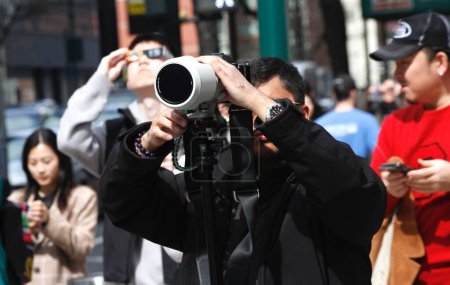Photo for Solar Eclipse Seen In New York. April 08, 2024, New York, USA :  New Yorkers and tourists stargazers are seen watching the solar eclipse in Manhattan. A solar eclipse occurs when the Moon passes between Earth and the Sun - Royalty Free Image
