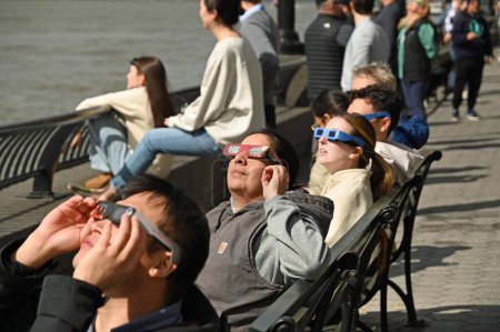 Téléchargez les photos : 8 avril 2024 - New York, USA : L'éclipse solaire de 2024 à New York. L'éclipse solaire tant attendue apparaîtra lorsque la lune bloquera les rayons du soleil lorsqu'elle passera entre le soleil et la terre. Personnes portant des lunettes de soleil spéciales - en image libre de droit