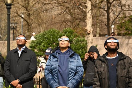 Foto de 8 de abril de 2024 - Nueva York, Estados Unidos: El eclipse solar de 2024 en la ciudad de Nueva York. El tan esperado eclipse solar aparecerá cuando la luna bloquee los rayos del sol mientras pasa entre el sol y la tierra. Personas que usan gafas de sol especiales - Imagen libre de derechos