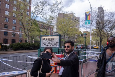 Téléchargez les photos : Le conférencier Johnson prononce un discours sur l'antisémitisme à l'Université Columbia. 24 avril 2024, New York, New York, États-Unis : Des gens posent pour un selfie avec des graffitis palestiniens gratuits devant l'université Columbia le 24 avril 2024 à New York. - en image libre de droit