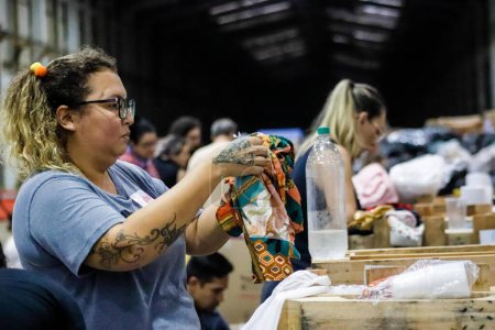 Foto de Passo Fundo (RS), 05 / 11 / 2024 - Mujer clasificando ropa en un área de recolección en la ciudad de Passo Fundo, este sábado (11), para organizar donaciones destinadas a víctimas de fuertes lluvias - Imagen libre de derechos