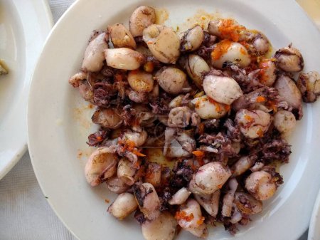 Téléchargez les photos : Gros plan de coquillages prises fraîches de la mer d'Espagne de palourdes et de crevettes et de poissons au citron et salade de tomate de laitue servi sur des assiettes blanches table en tissu de lin dans le restaurant vue sur la plaine - en image libre de droit