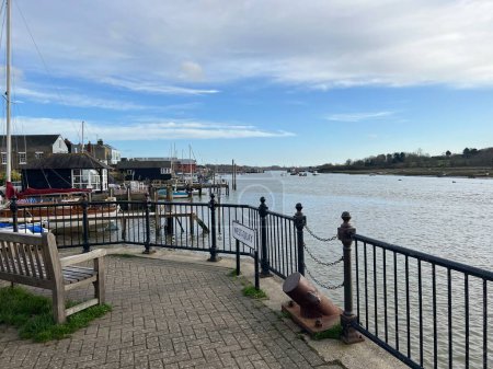 Téléchargez les photos : Wivenhoe, Essex East Anglia uk - January 11 2023: Panoramic landscape view of the harbour at  on a Winter day with water boat moorings and cottage buildings  by promenade walk blue sky - en image libre de droit