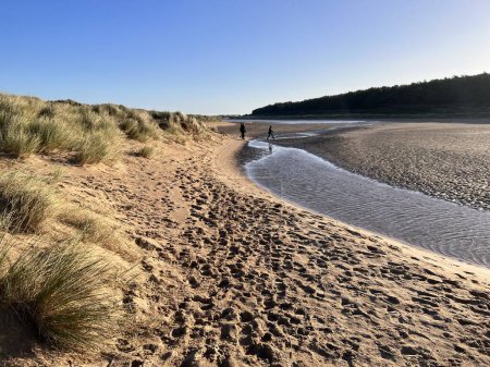 Photo for Beautiful landscape of beach at Holkham with pool of sea salt water between grassy sand banks on cold tranquil bright Winter day with blue skies in Norfolk East Anglia uk on holiday walk - Royalty Free Image