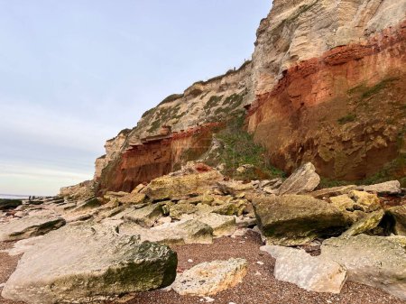 Photo for Prehistoric cliff landscape at Hunstanton beach Norfolk of layers of millions of years old formations in white and rust colour with fossils trapped in stone on beautiful Spring day - Royalty Free Image