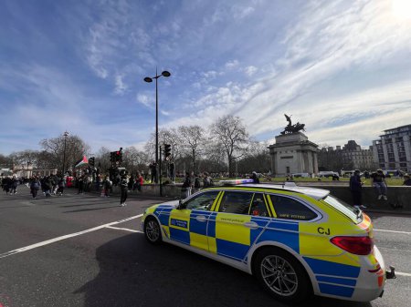 Photo for London, England, UK - March 9 2024: Police guarding peaceful anti- war coalition protest from Hyde Park to US embassy for ceasefire in Gaza Middle East groups include Muslims Jews Christians marching with colourful  flags banners by Wellington arch - Royalty Free Image