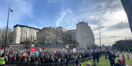 Photo for London, England, UK - March 9 2024: Peaceful anti- war coalition protest for ceasefire in Gaza Middle East from Hyde Park to US embassy groups include Muslims Jews Christians marching and chanting with flags and banners under blue skies - Royalty Free Image