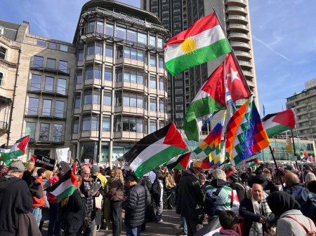 Photo for London, England, UK - March 9 2024: colourful flags and crowds at peaceful anti- war coalition protest from Hyde Park to US embassy for ceasefire in Gaza Middle East groups include Muslims Jews Christians marching chanting buildings under blue sky - Royalty Free Image