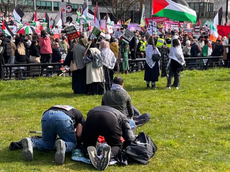 Photo for Muslims praying on grass in London, England, UK - March 9 2024 at peaceful anti- war coalition protest for ceasefire in Gaza Middle East from Hyde Park to US embassy groups include Muslims Jews Christians marching and chanting with flags and banners - Royalty Free Image