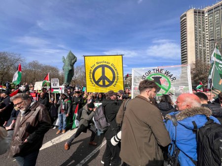 Photo for Hyde Park, London, England, UK - March 9 2024: CND group banner at peaceful anti- war coalition protest march to US embassy for ceasefire in Gaza Middle East groups include Muslims Jews Christians marching with colourful  flags banners police protact - Royalty Free Image