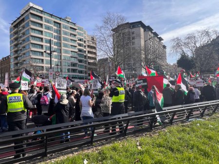 Foto de Londres, Inglaterra, Reino Unido - 9 de marzo de 2024: Protesta pacífica de la coalición contra la guerra por el alto el fuego en Oriente Medio desde Hyde Park a grupos de embajadas estadounidenses incluye musulmanes judíos cristianos marchando y coreando con banderas y pancartas - Imagen libre de derechos