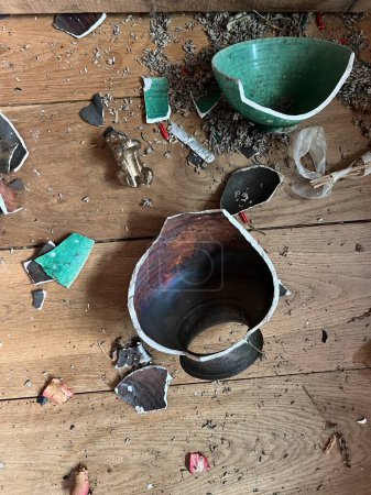 Photo for Close up of broken ceramic art and antique china vase, vintage bowl contain lavender and plates shapes and colour pieces destroyed by fall from collapsed mantelpiece to oak wood floor in old house - Royalty Free Image